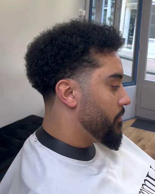 Curly top with a fade and full beard