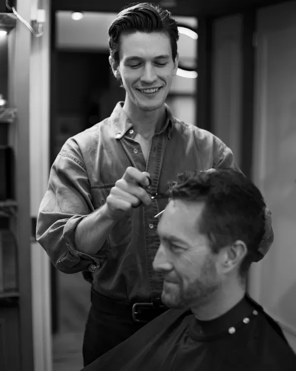 Ryan cutting a client's hair, black and white